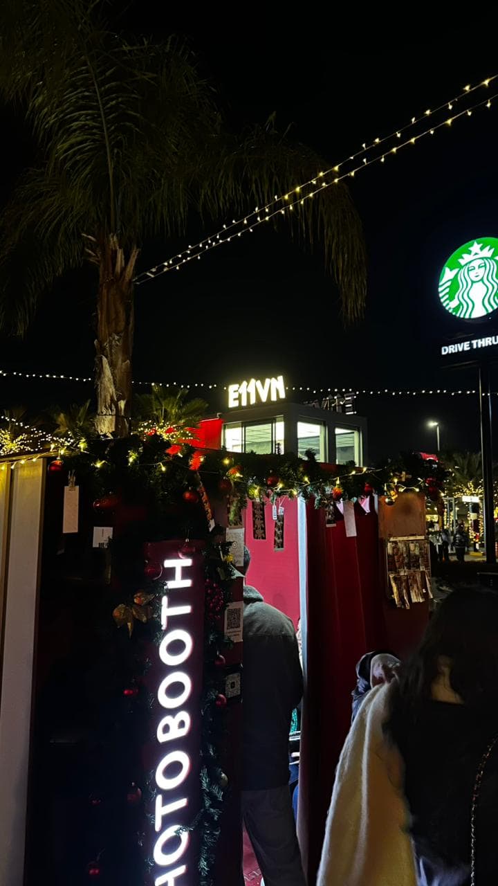 The black photo booth among festive string lights at The Drive at night